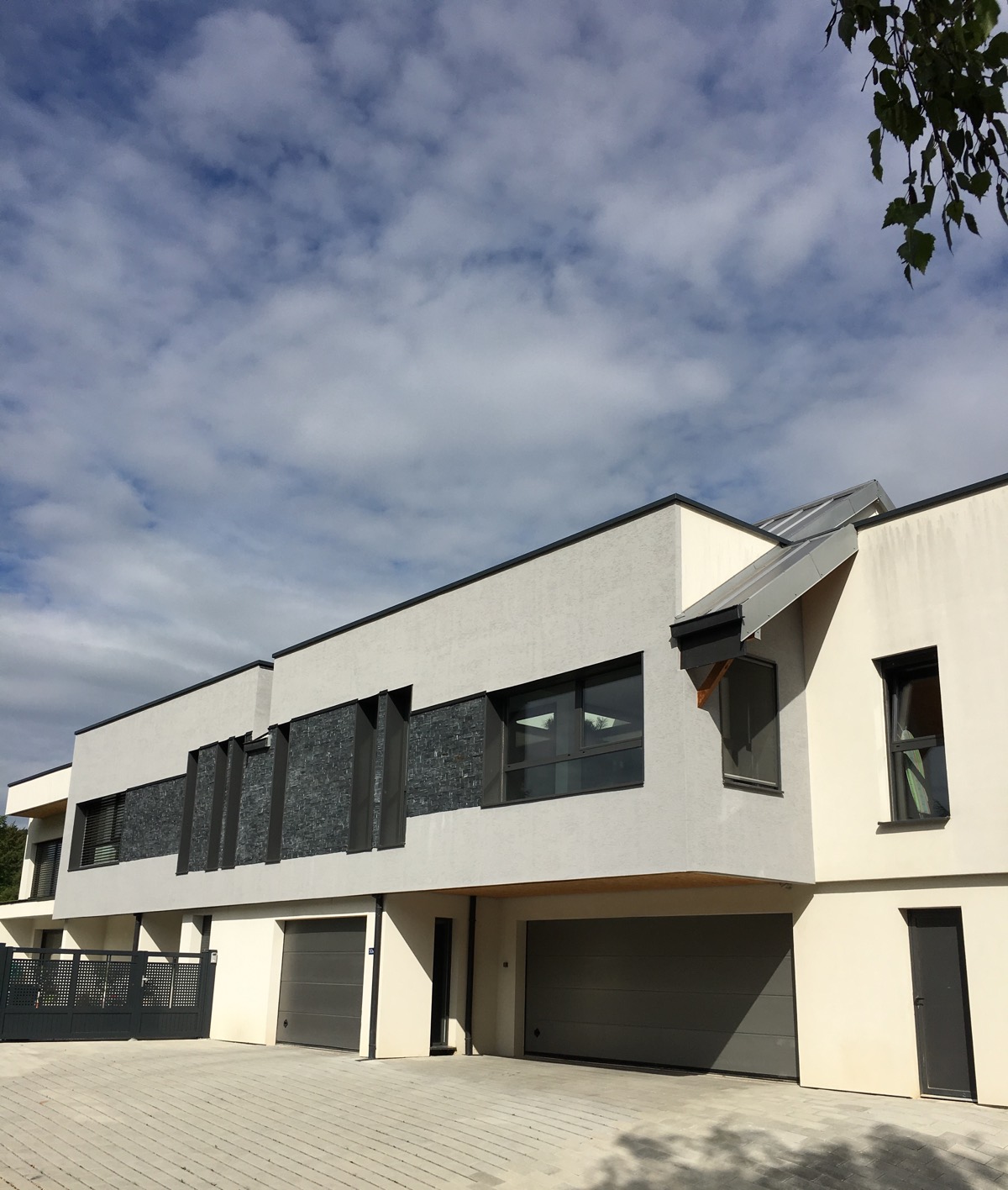 Maison contemporaine à toit plat, enduit blanc et parements de pierre, réalisée par Home Création